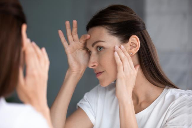 אישה בוחנת את עור הפנים אחרי טיפול פילינג